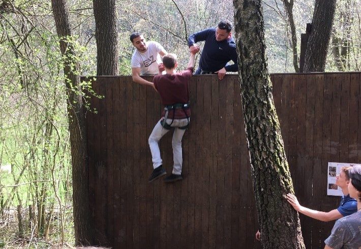 Leerlingen klimmen over een muur
